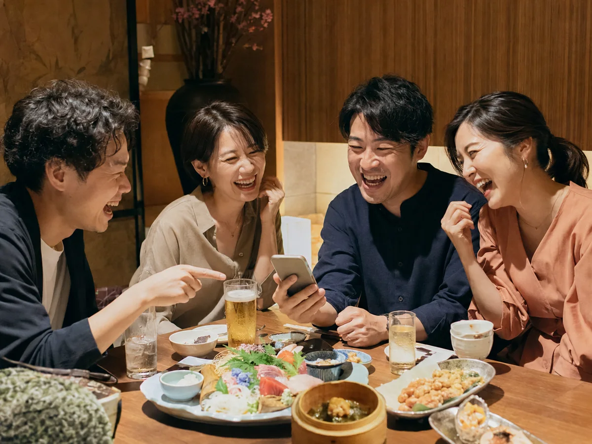 飲み会でスマートフォンのパーティーゲームを楽しむ4人の友人